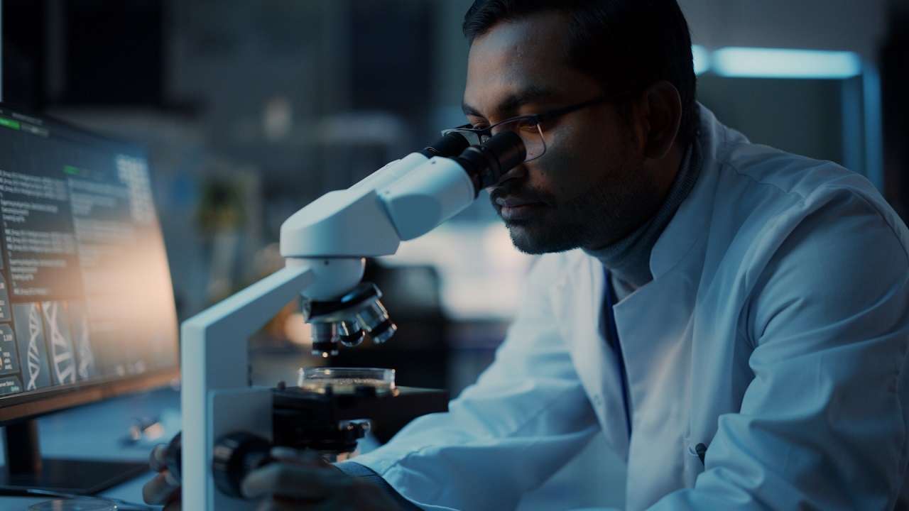 Man with glasses looking through microscope