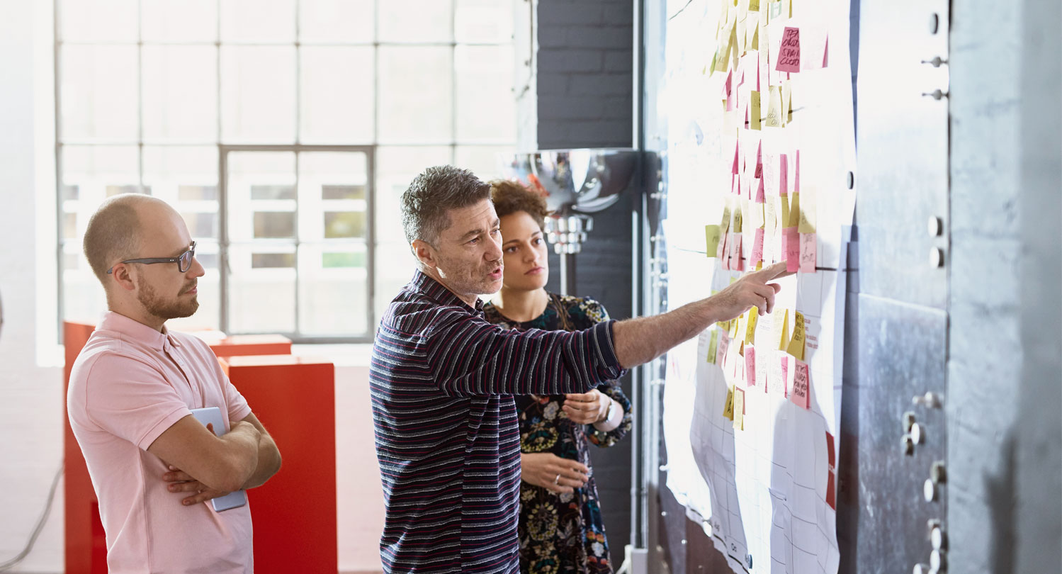 3 people in a meeting looking at a board