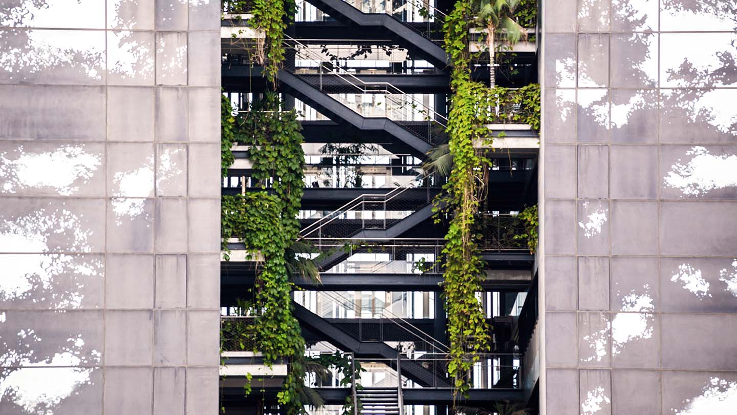 Outdoor steel stairs of glass building with greenery on each side