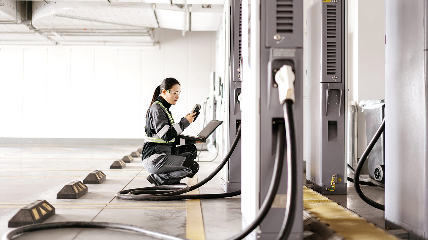 Worker holding a laptop in a parking lot for electronic vehicles