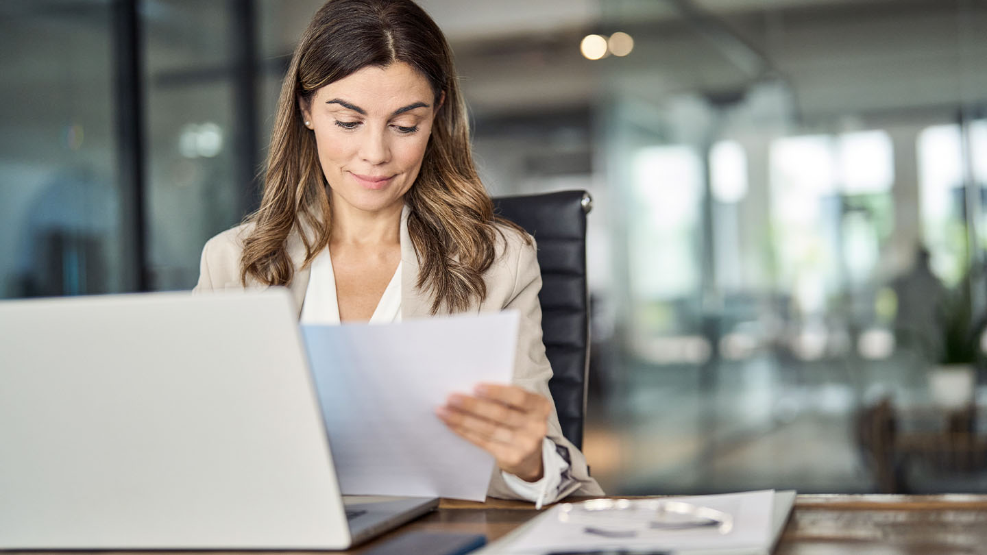 Professional with laptop looking at paper