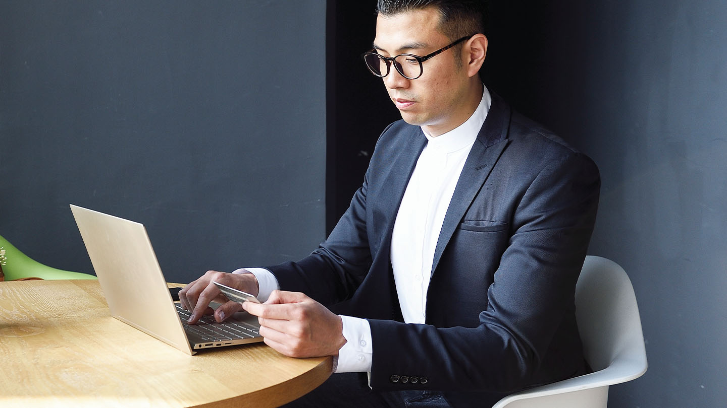 Man using credit card on his laptop banner