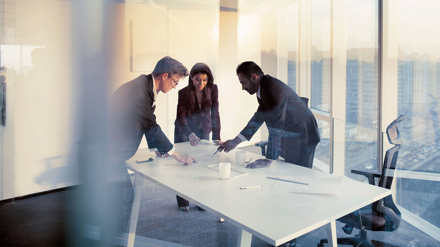 three people in a meeting room banner