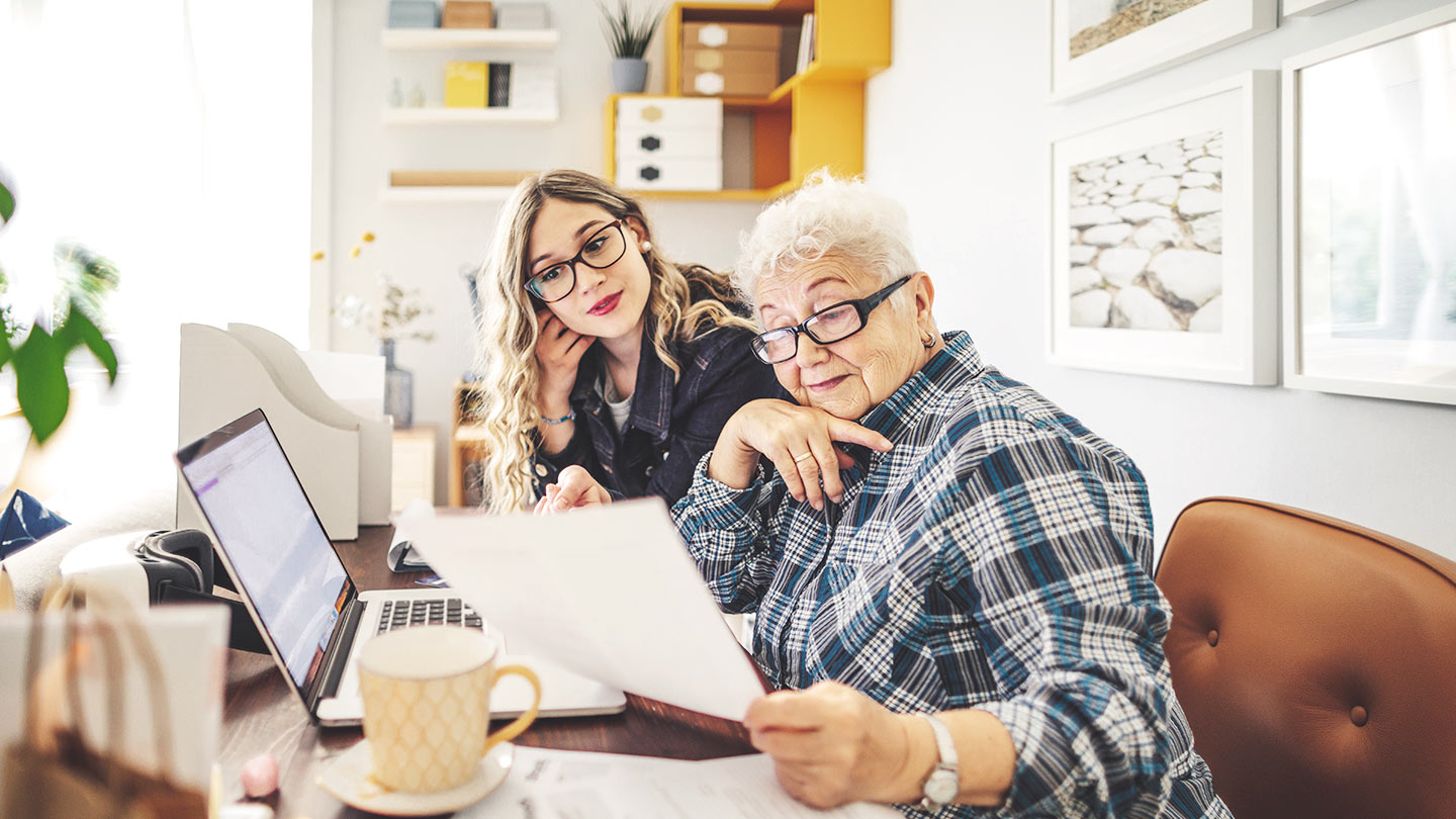 Real estate owner and her adult daughter look over a document while sitting at a desk