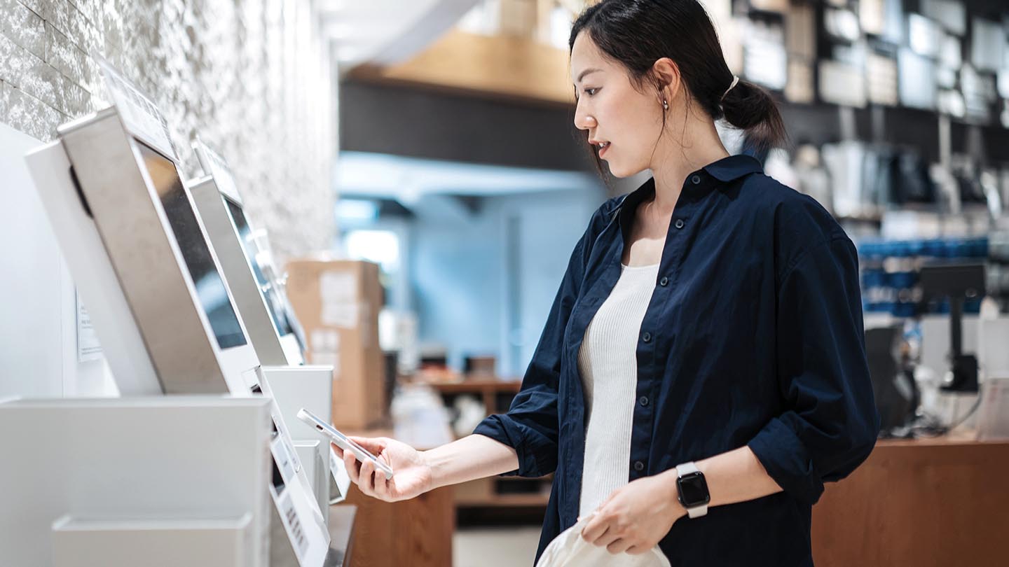 Woman holding her phone to a kiosk