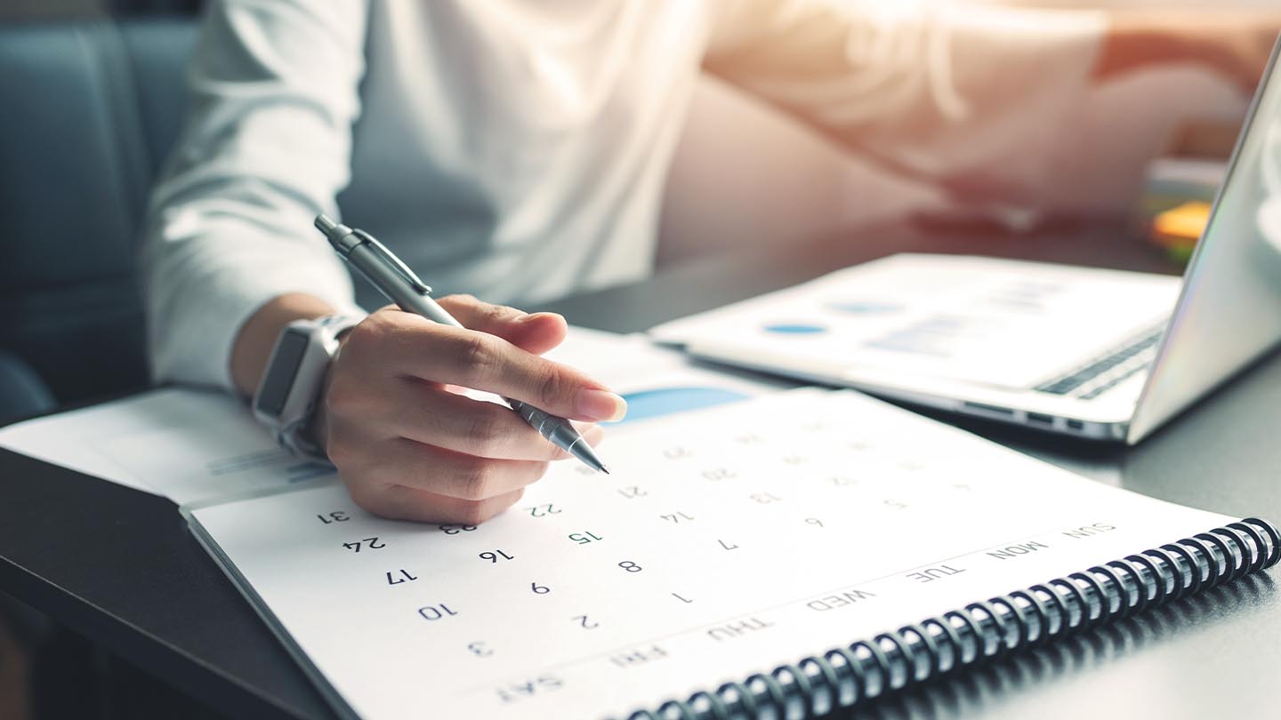 Individual holding a pen to a calendar 