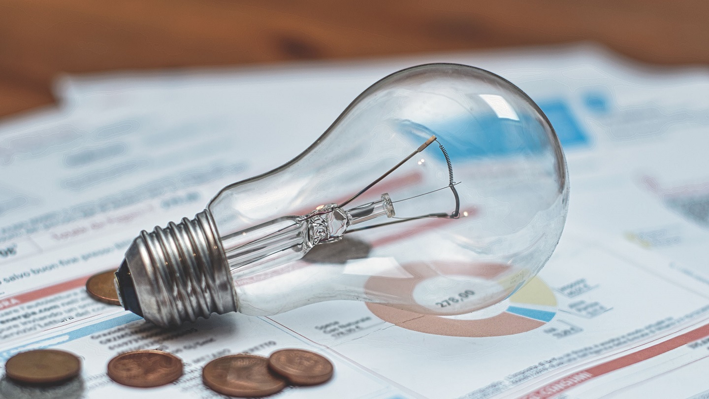 Detail of electricity bills with light bulb and coins