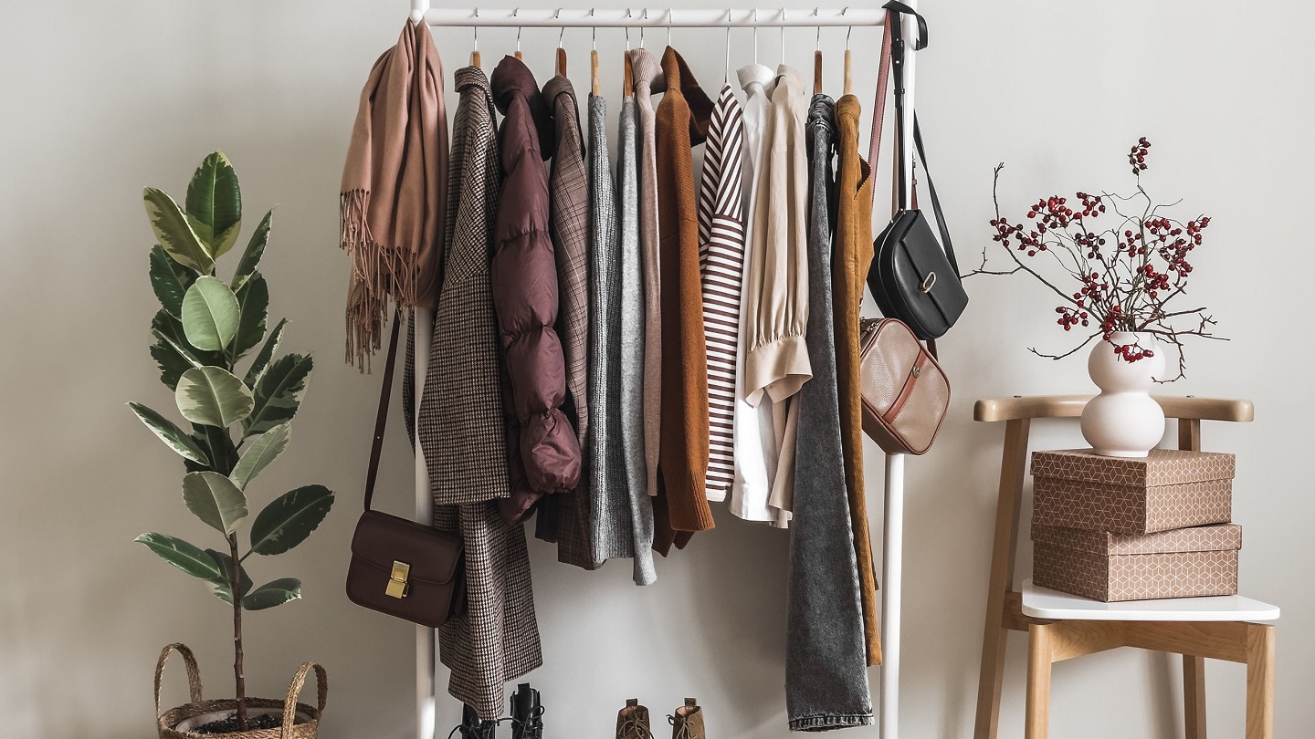 Cozy dressing room. Floor hanger with women's seasonal autumn winter clothes. Coats, pullovers, jackets, shirts, shoes - comfortable casual women's clothing