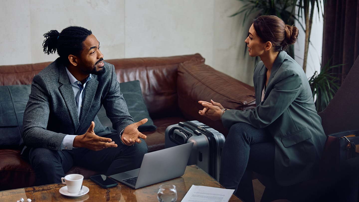 African American entrepreneur talking to female colleague during business meeting in hotel lobby.