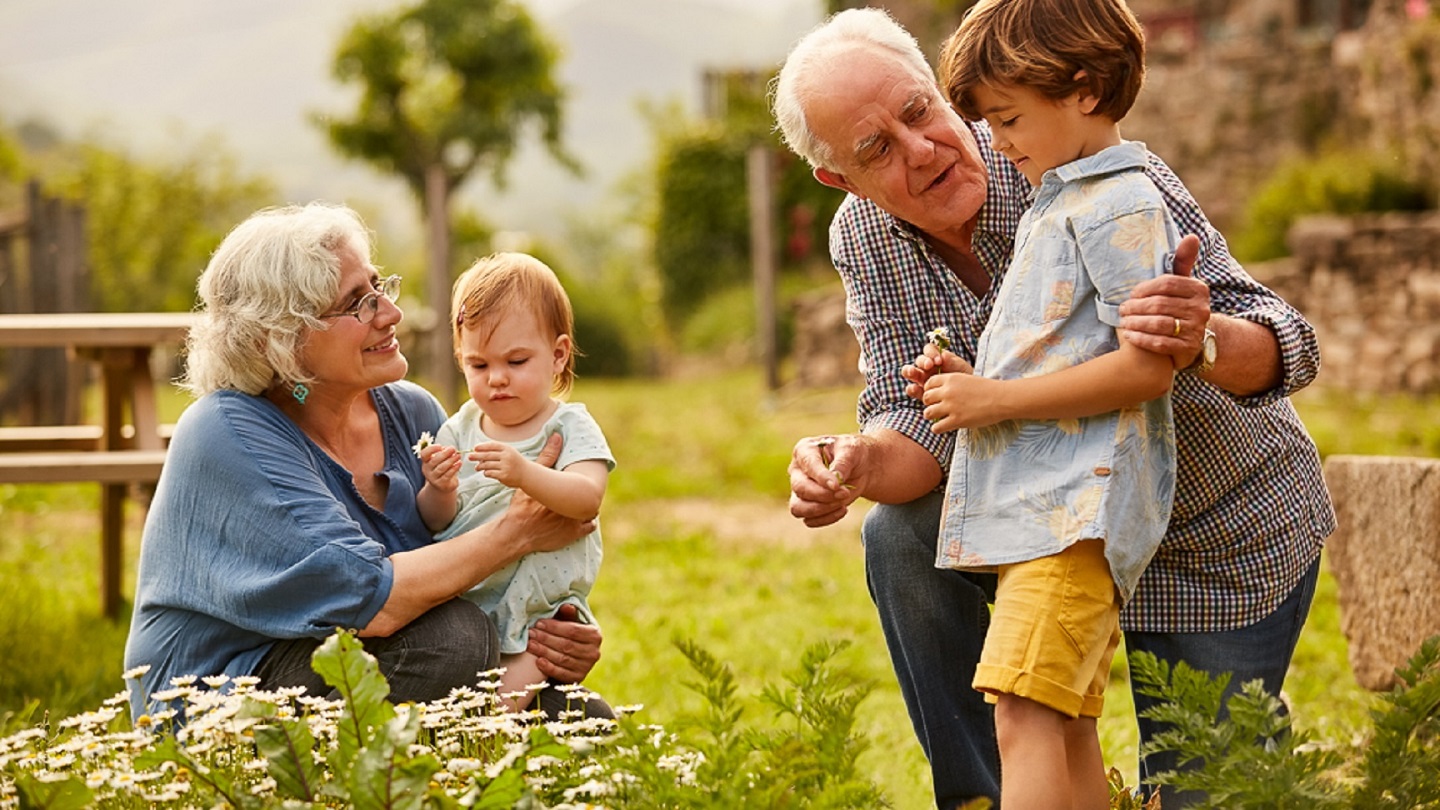 Grandparents talking to children. Family having leisure time in yard. They are wearing casuals.