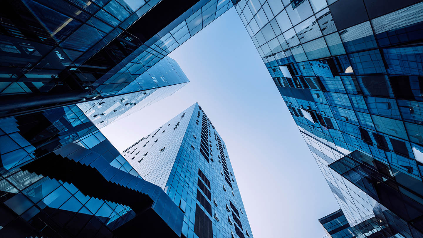 Skyward view of sleek modern office buildings with glass facades reflecting the sky in Beijing, China. The architecture showcases urban development and corporate infrastructure.