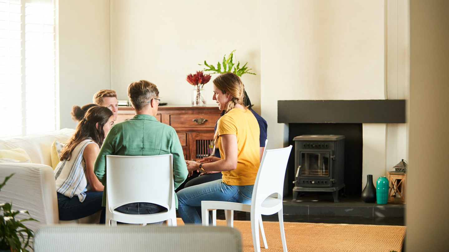 Diverse group of young people talking together while sitting in a circle during a support group meeting at a friend's home